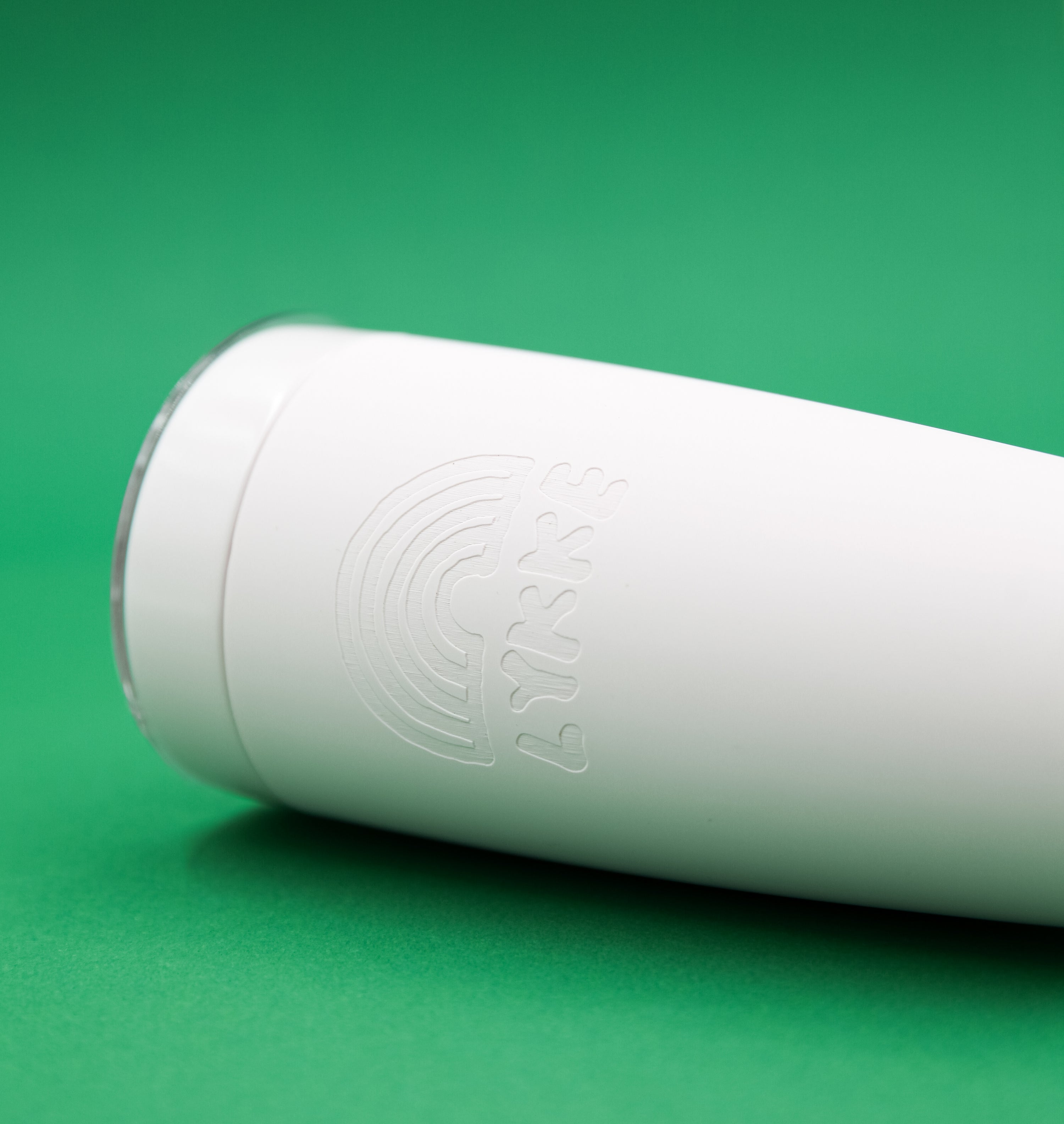 Pink tumbler with embossed design on a green background