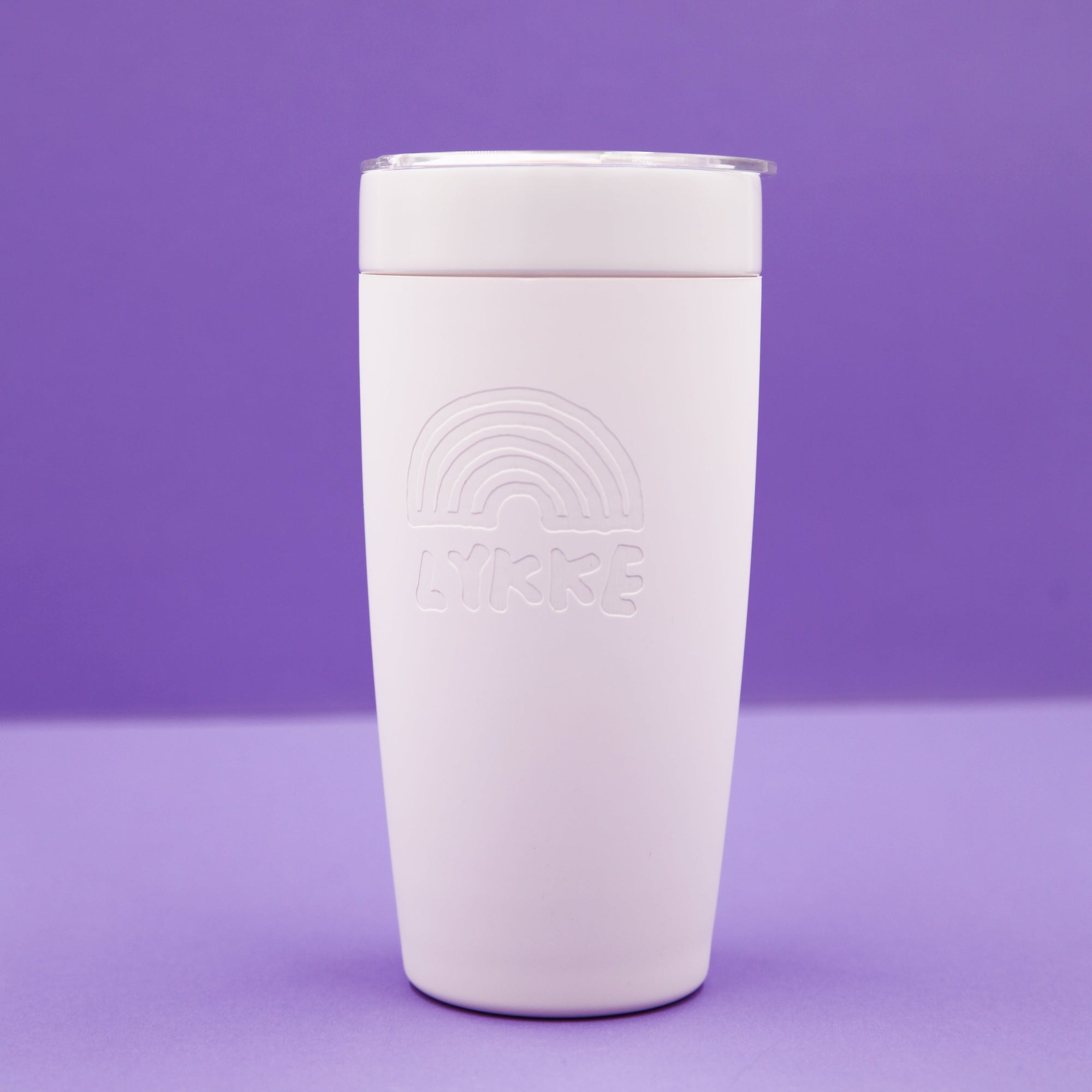 Pink tumbler with embossed design on a purple background