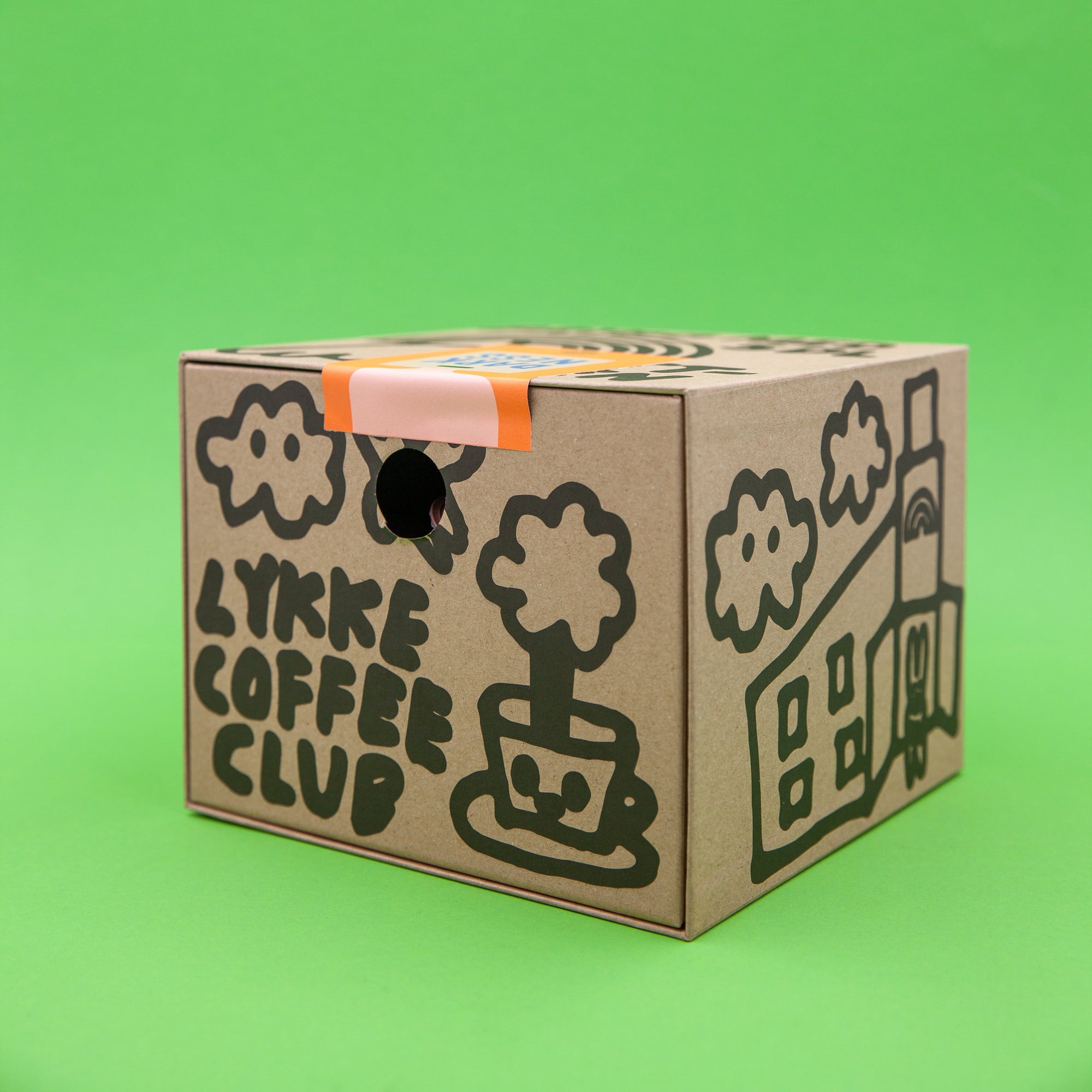 Cardboard box with 'Lykke Coffee Club' branding on a green background